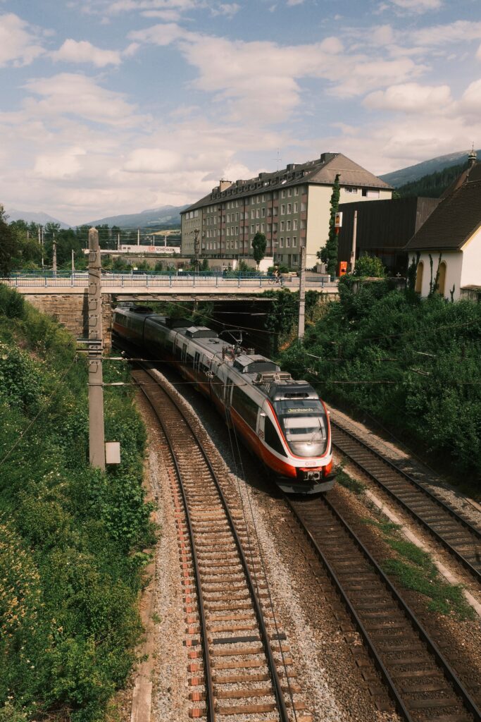 A connecting train travels through picturesque Innsbruck under a clear sky in summer.